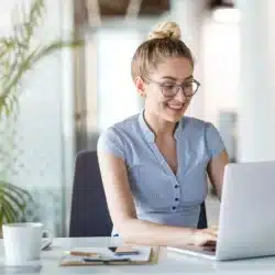 mujer sonriendo escribiendo en un portatil